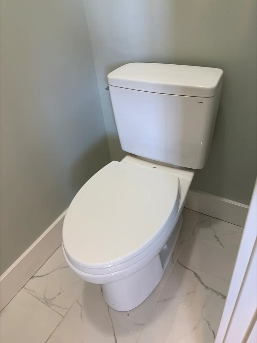 A white Toto toilet on a marble-look tile floor.