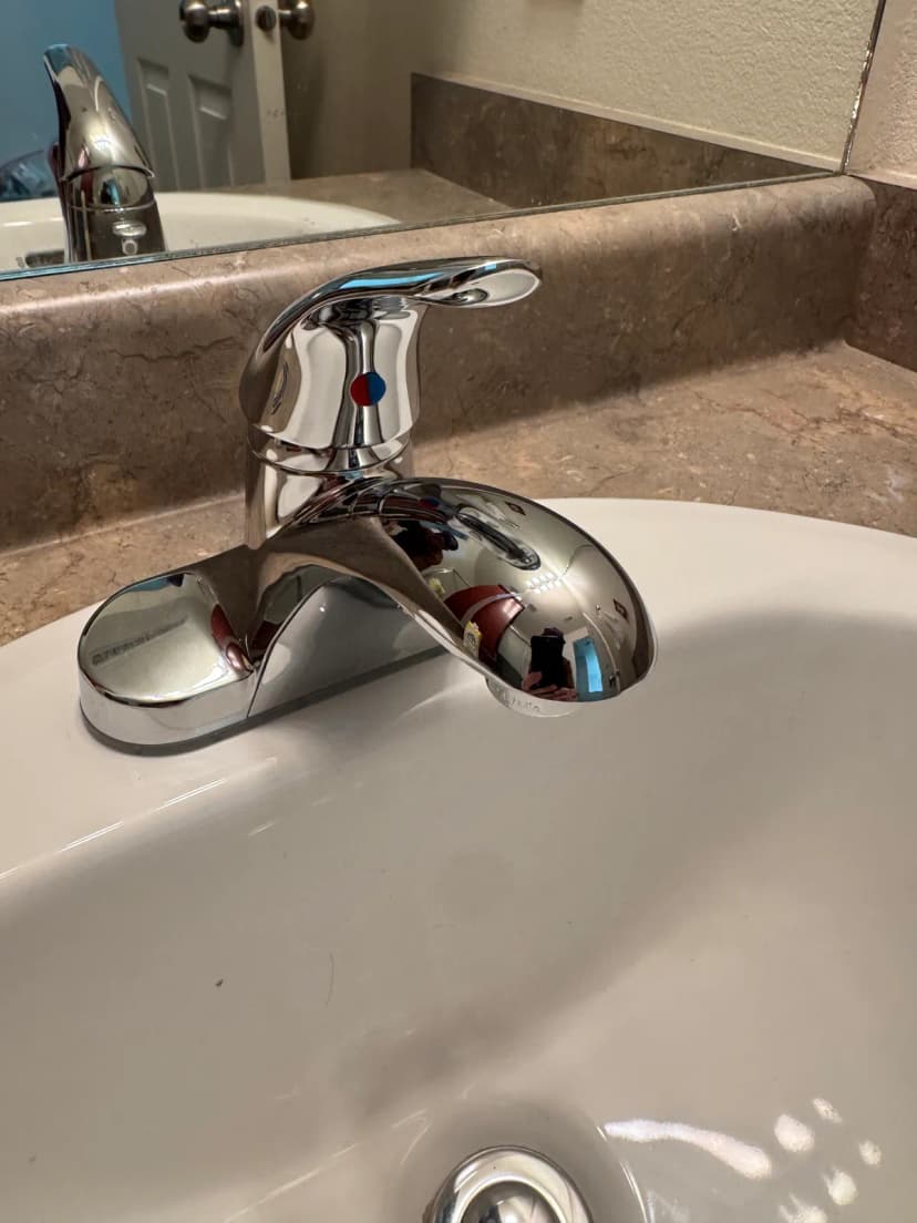 A chrome single-handle faucet on a white sink set in a brown countertop.