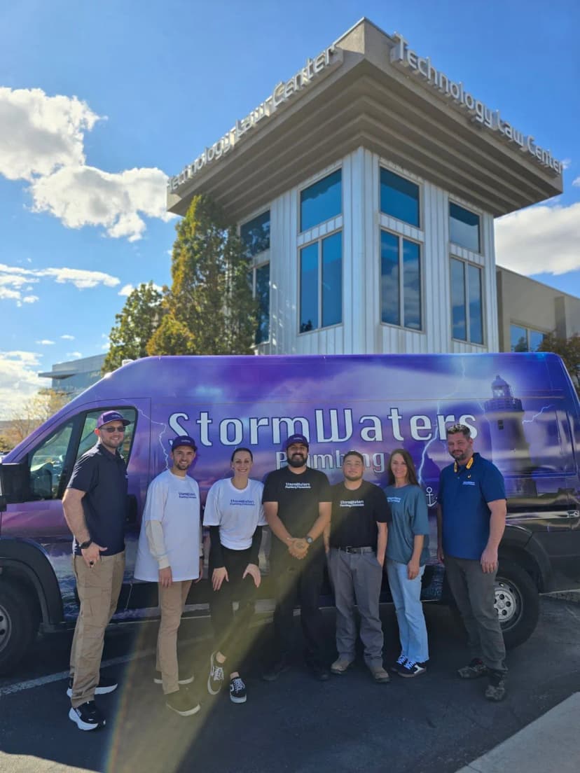 Siete personas con camisetas de StormWaters de pie frente a la camioneta de StormWaters Plumbing.